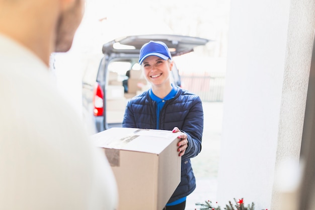 Kostenloses Foto netter kurier, der dem kunden paket gibt