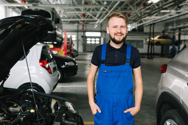 Netter Mechaniker, der nahe Autos steht