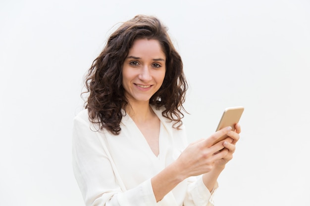 Netter positiver weiblicher Smartphonebenutzer, der Gerät hält