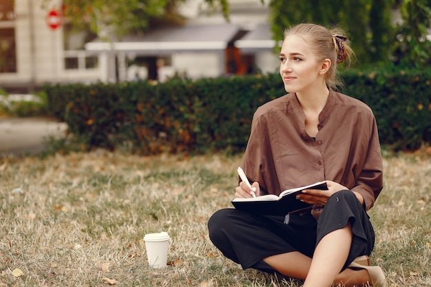 Netter Student, der in einem Park arbeitet und das Notizbuch benutzt