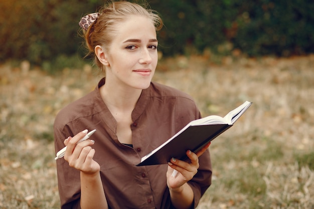 Netter Student, der in einem Park arbeitet und das Notizbuch benutzt