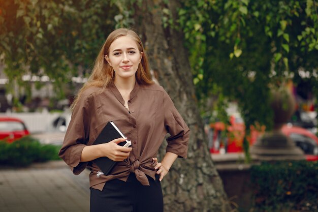 Netter Student, der in einem Park arbeitet und das Notizbuch benutzt