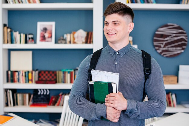 Netter Student mit Lehrbuch und Notizbuch