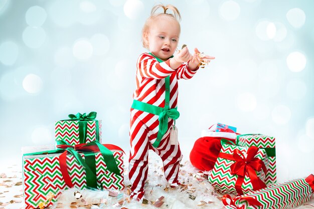 Nettes Baby 1 Jahr alt, das Weihnachtsmannmütze trägt, der über Weihnachten aufwirft