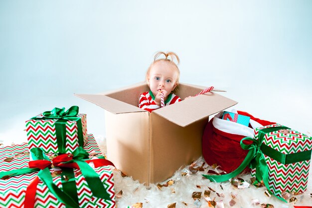 Nettes Baby, das im Kasten über Weihnachtshintergrund sitzt. Urlaub, Feier, Kinderkonzept