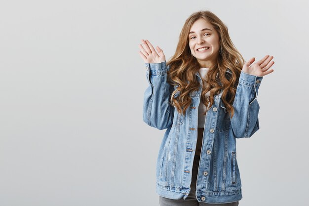 Nettes blondes Mädchen, das ahnungslos die Hände erhebt, lächelt und sich dafür entschuldigt, ahnungslos zu sein