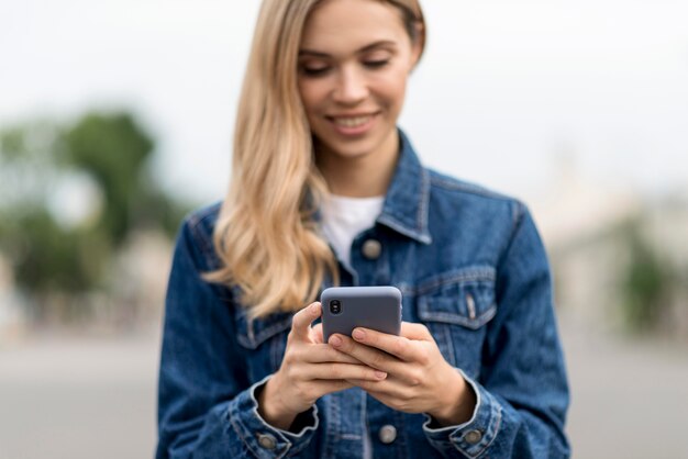 Nettes blondes Mädchen, das ihr Handy benutzt