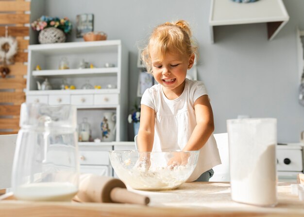 Nettes blondes Mädchen, das Teig zubereitet