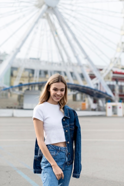 Nettes blondes Mädchen, das vor Riesenrad aufwirft