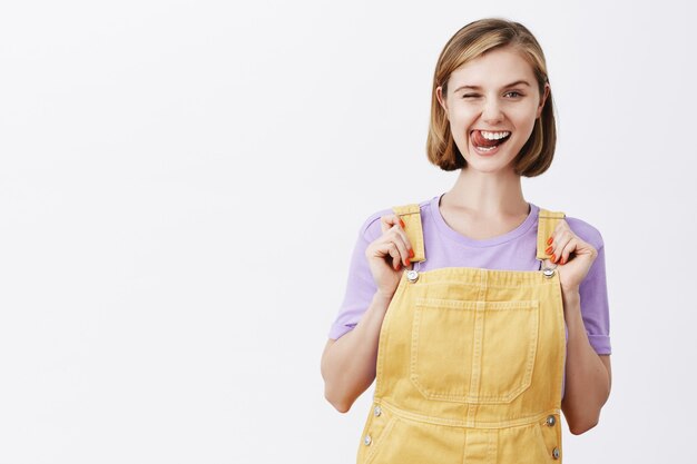 Nettes blondes Mädchen, das Zunge zeigt und glücklich lächelt