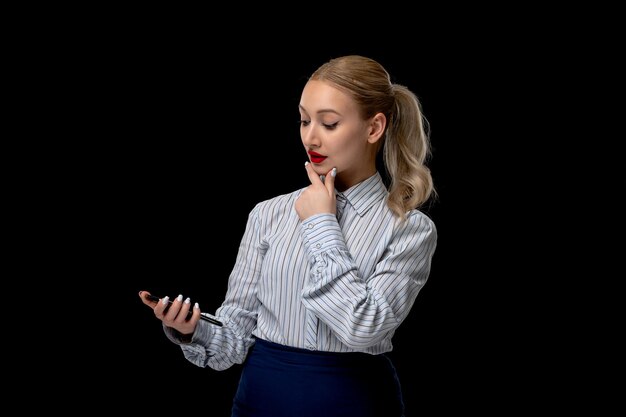 Nettes blondes Mädchen der Geschäftsfrau, das den Telefonbildschirm mit rotem Lippenstift im Bürokostüm betrachtet