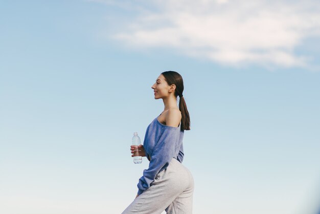 Nettes junges Frauentraining mit Flasche Wasser