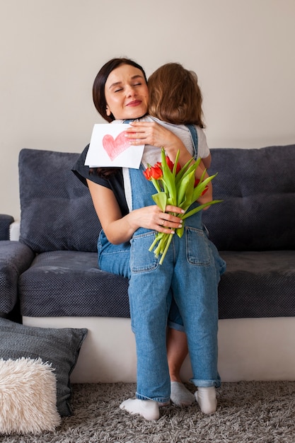 Nettes junges Mädchen, das ihre schöne Mutter umarmt