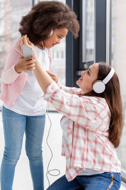 Nettes junges Mädchen, das mit ihrer Mutter zu Hause spielt