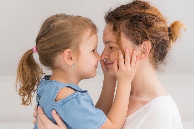 Nettes junges Mädchen, das Mutter zu Hause umarmt