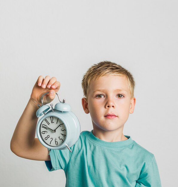 Nettes Kind der Vorderansicht, das eine Uhr hält