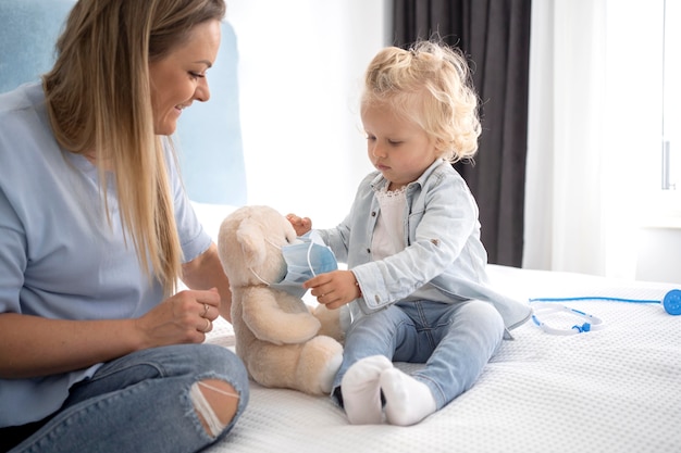 Nettes Kind mit Spielzeug und Stethoskop zu Hause während der Quarantäne