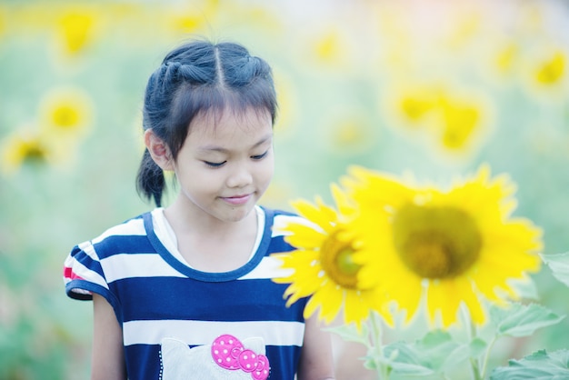 Nettes Kindermädchen mit Sonnenblume auf dem Sommergebiet