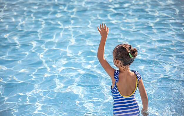 Nettes kleines Mädchen badet in einem Pool in klarem Wasser.
