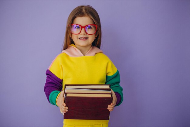 Nettes kleines Mädchen, das Bücher isoliert im Studio hält