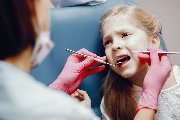 Nettes kleines Mädchen, das im Büro des Zahnarztes sitzt