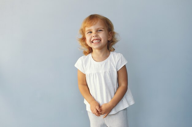 Nettes kleines Mädchen, das in einem Studio auf einem blauen Hintergrund sitzt