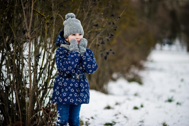 Nettes kleines Mädchen, das sich am Wintertag im Freien amüsiert