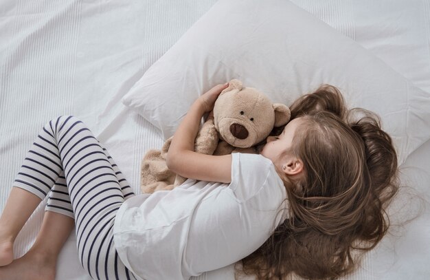 Nettes kleines Mädchen im Bett mit Stofftier.