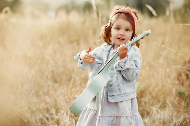 Nettes kleines Mädchen in einem Park, der auf einer Gitarre spielt