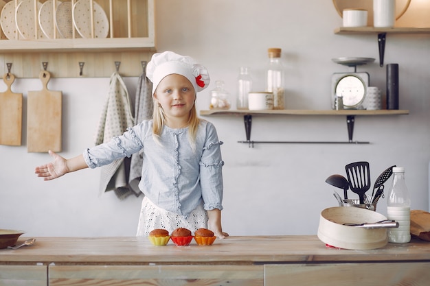 Kostenloses Foto nettes kleines mädchen in einer küche mit kleinem kuchen
