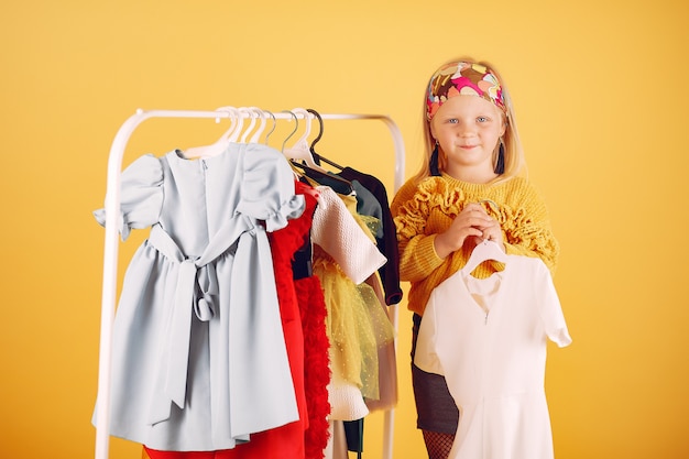Nettes kleines Mädchen mit Einkaufstaschen auf einem gelben Hintergrund