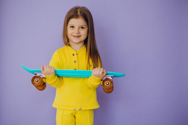 Nettes kleines Mädchen mit Skateboard im Studio