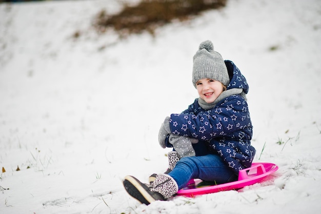 Nettes kleines Mädchen mit Untertassenschlitten draußen am Wintertag