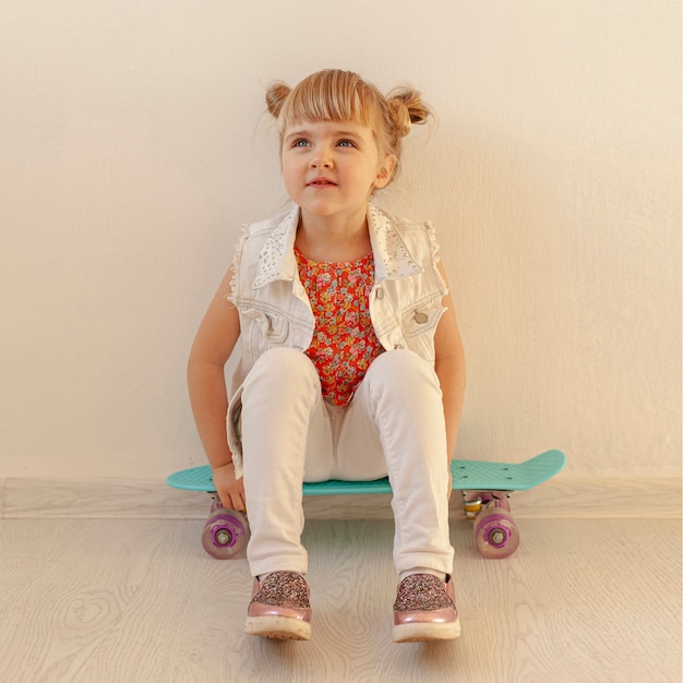 Kostenloses Foto nettes kleinkind, das auf skateboard aufwirft