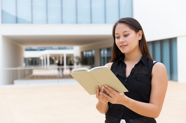 Nettes lächelndes Studentinleselehrbuch