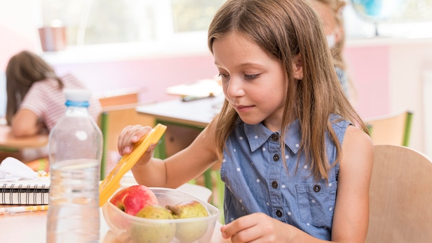 Nettes Mädchen, das am Schulkonzept isst