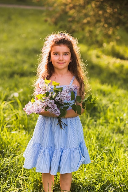 Nettes Mädchen, das auf Gras mit dem Halten des Blumenbündels steht