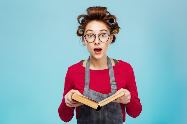 Kostenloses Foto nettes mädchen, das brille und lockenwickler trägt, sieht beim lesen überrascht aus