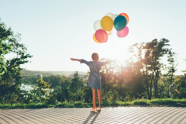 Nettes Mädchen, das bunte Luftballons im Stadtpark hält