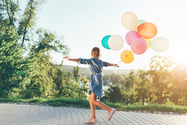 Nettes Mädchen, das bunte Luftballons im Stadtpark hält