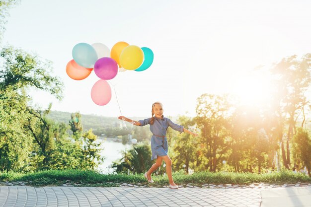 Nettes Mädchen, das bunte Luftballons im Stadtpark hält