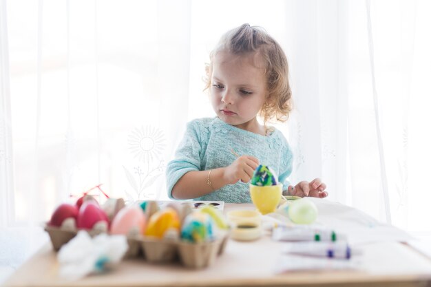 Nettes Mädchen, das Eier für Ostern verziert