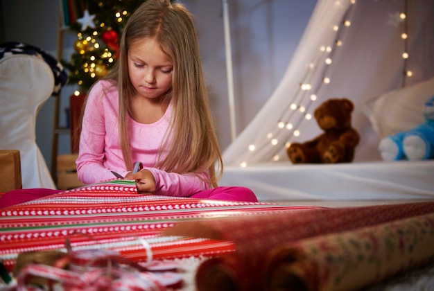 Nettes Mädchen, das ein Geschenkpapier schneidet