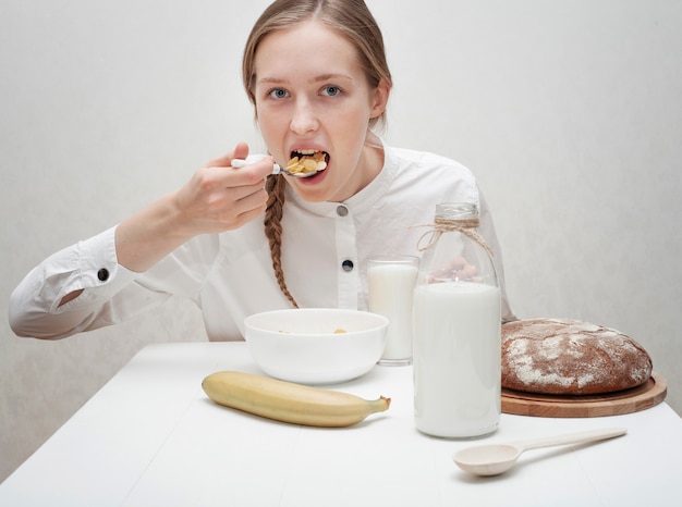 Nettes Mädchen, das Getreide mit Milch isst