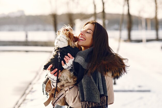 Nettes Mädchen, das in einem Winterpark mit ihrem Hund geht