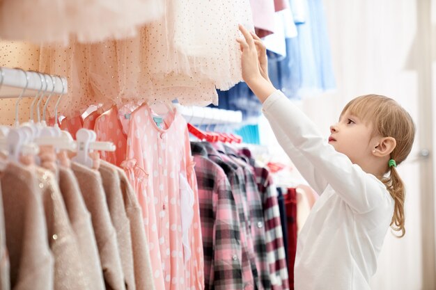 Nettes Mädchen, das moderne, stilvolle Kinderkleidung wählt.