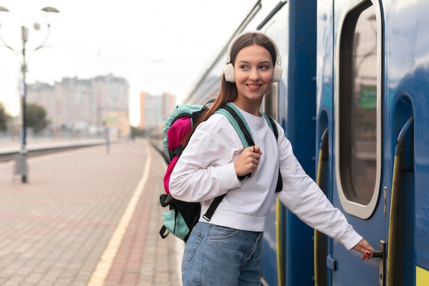 Nettes Mädchen der Seitenansicht am Bahnhof, der den Zug betritt