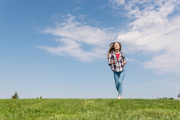 Nettes Mädchen der Vorderansicht, das auf Gras läuft