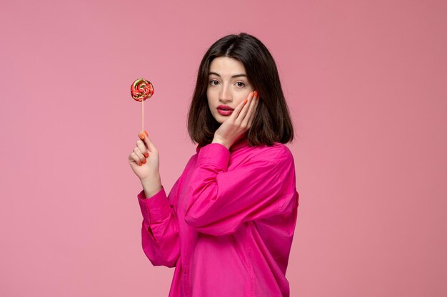 Nettes Mädchen hübsche junge schöne Brünette Mädchen rosa Hemd mit Gesicht und runden süßen Lutscher