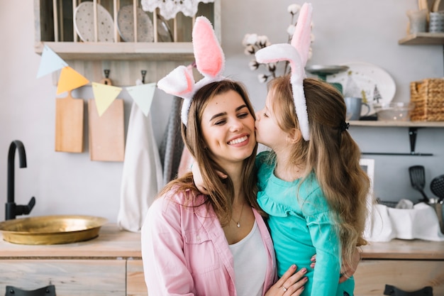 Kostenloses Foto nettes mädchen in den häschenohren mutter auf backe küssend